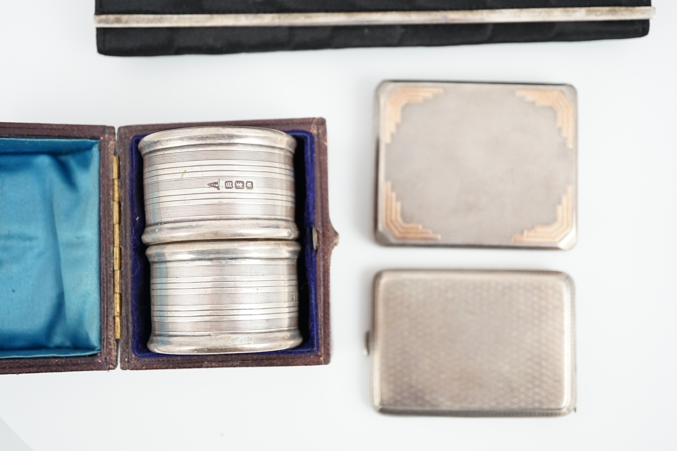 An Art Deco engine turned silver match sleeve by Asprey & Co, Birmingham, 1933, 6cm, together with one other silver match sleeve, a cased pair of silver napkin rings and a continental silver mounted four piece vanity set